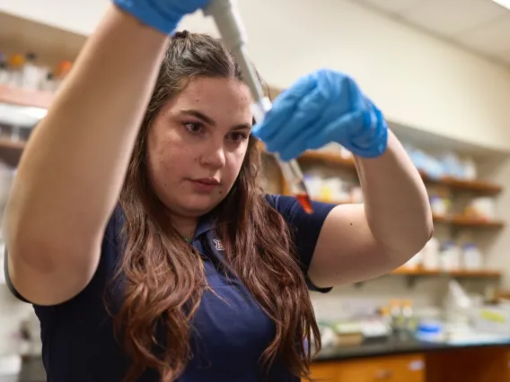 Yound woman working in a lab with a pipette and vial