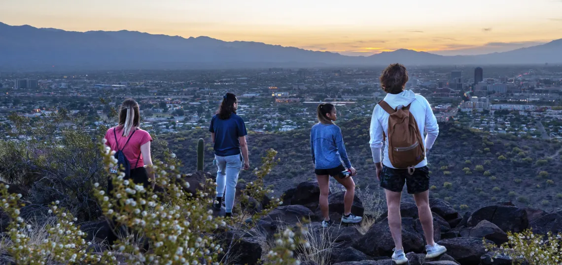 4 students on top of Tumamoc hill looking out at the sunset