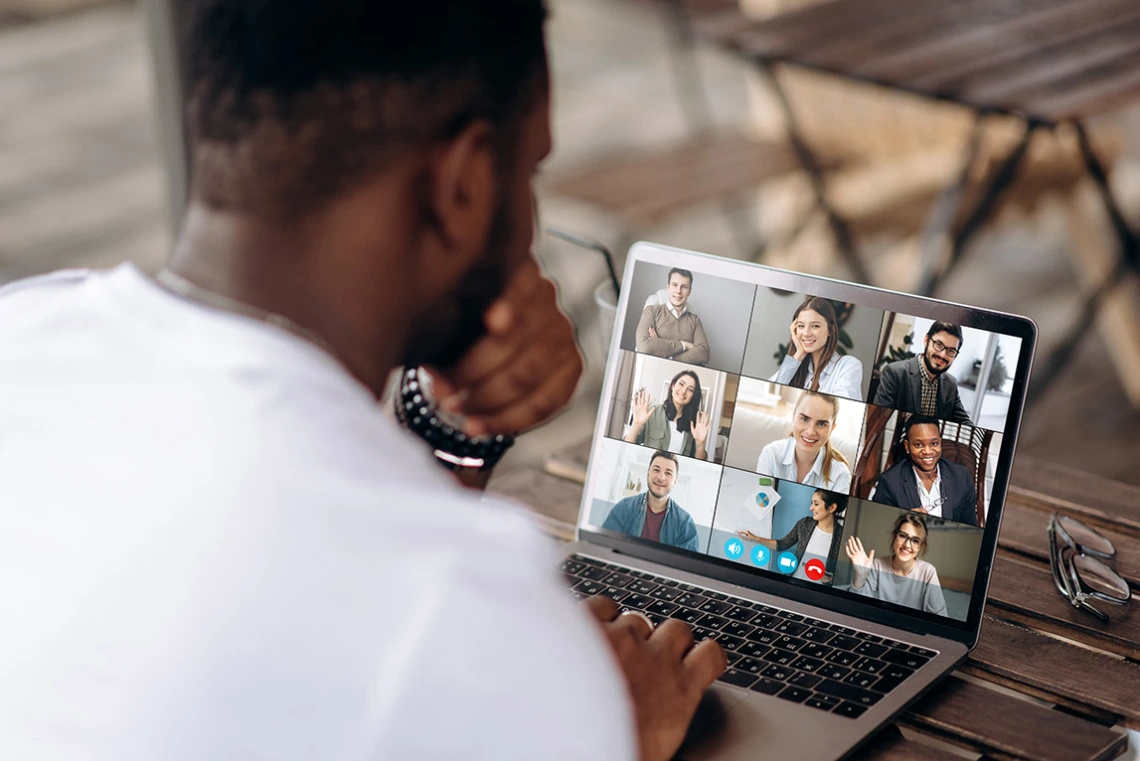 Man at a laptop displaying a video conference call